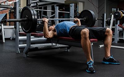 A lifter pressing a barbell on a flat bench